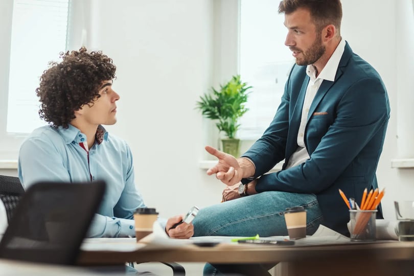 Twee collega’s in een feedbackgesprek aan tafel