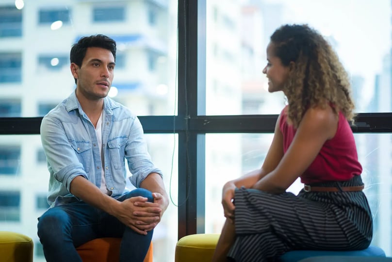Twee collega’s in een een-op-eengesprek bij het raam