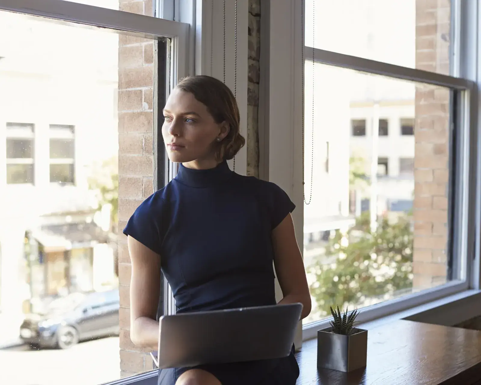 HR-professional werkt aan de business case achter haar laptop bij het raam