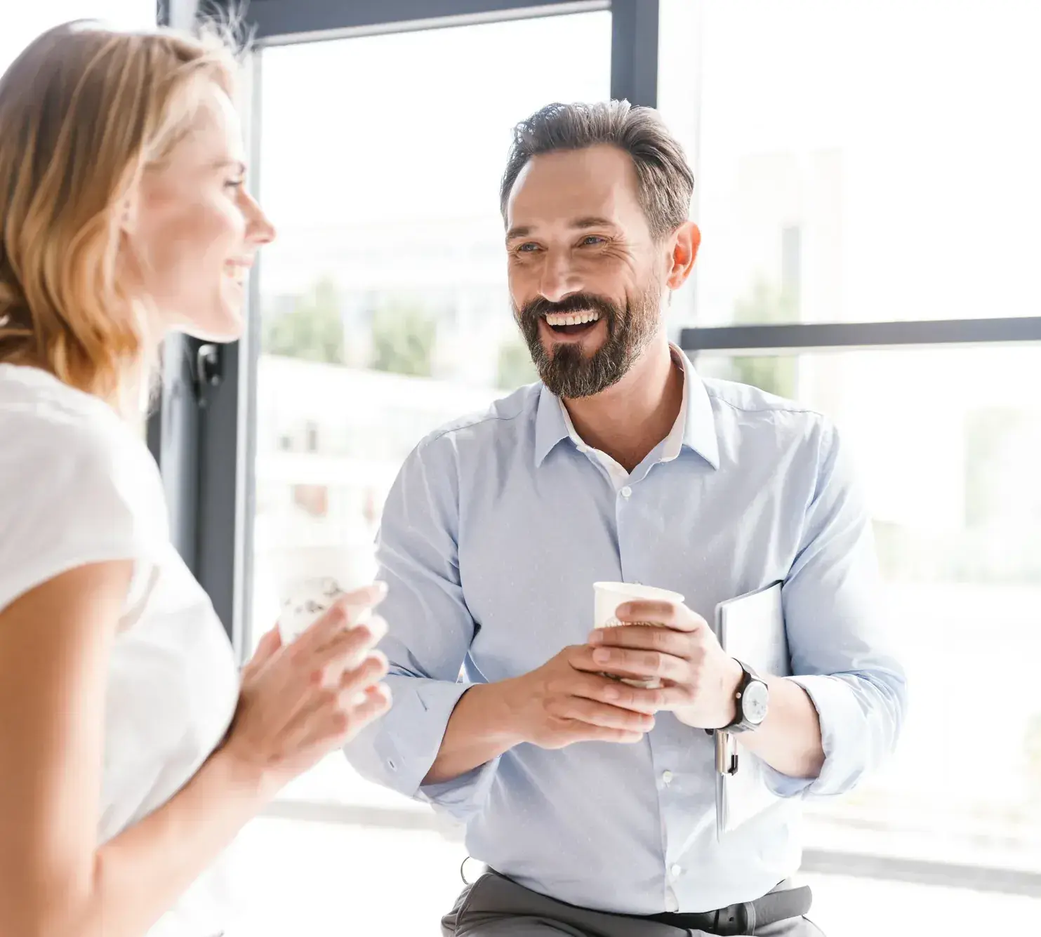 Manager en medewerker wisselen lachend feedback uit bij de koffie