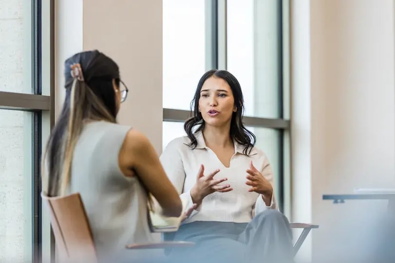 Twee collega’s in gesprek bij een groot raam