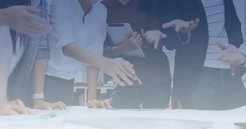 Handen van collega’s die samen naar een plan op tafel wijzen