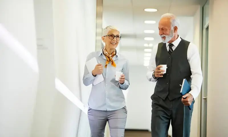 Twee collega’s lopen in gesprek door een lichte gang