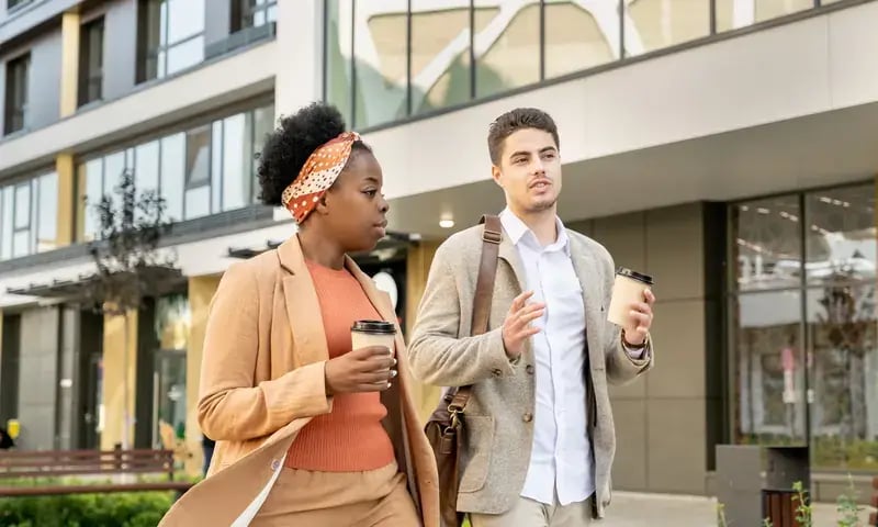 Twee collega’s lopen met koffie door de stad