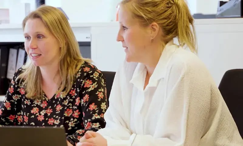 Twee collega’s van de KNVB werken samen aan hun bureau