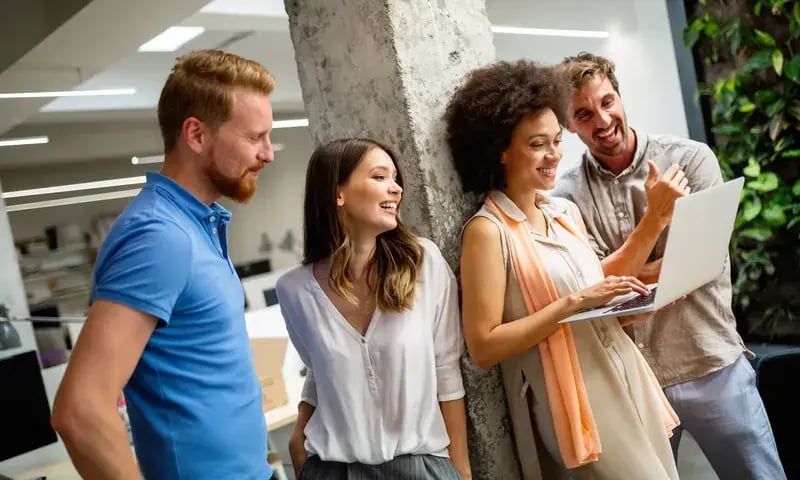 Collega’s lachen samen rond een laptop