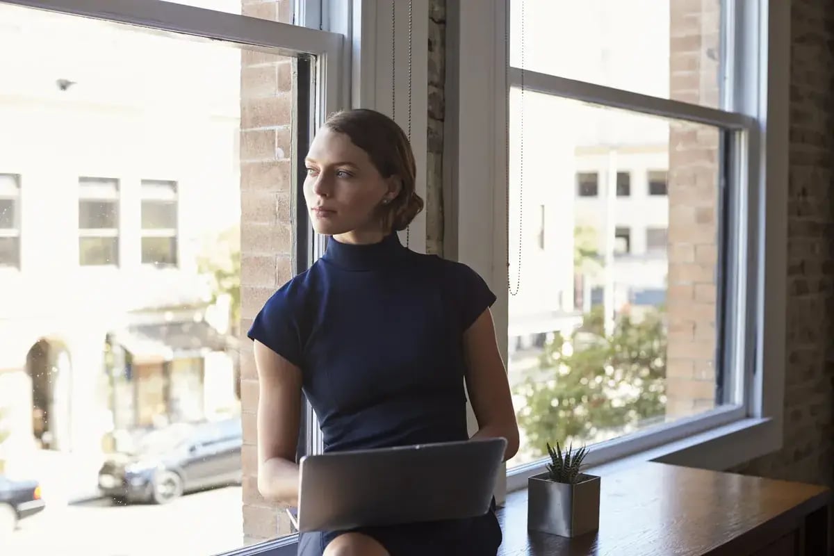 Een medewerker werkt op haar laptop bij het raam