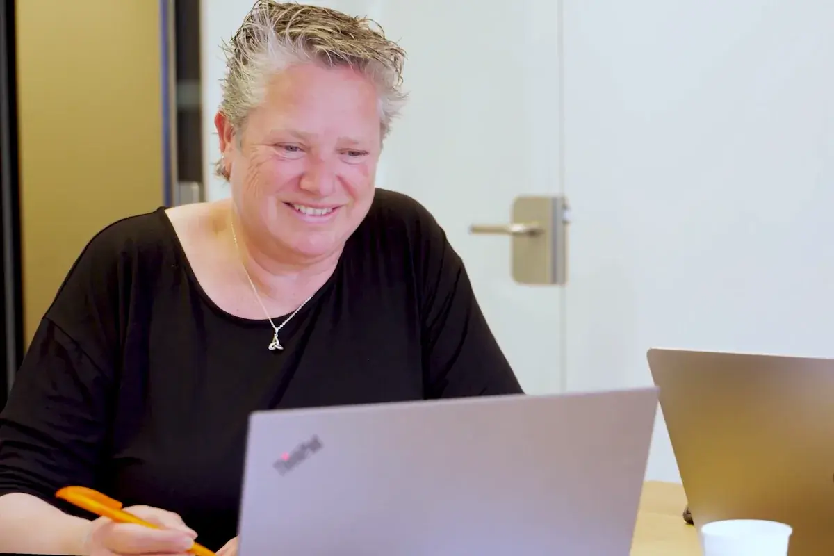 Een collega van de KNVB lacht achter haar laptop