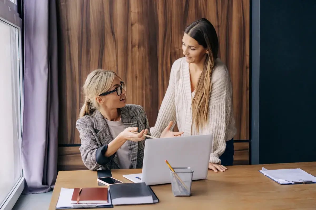 Twee collega’s werken samen aan een laptop