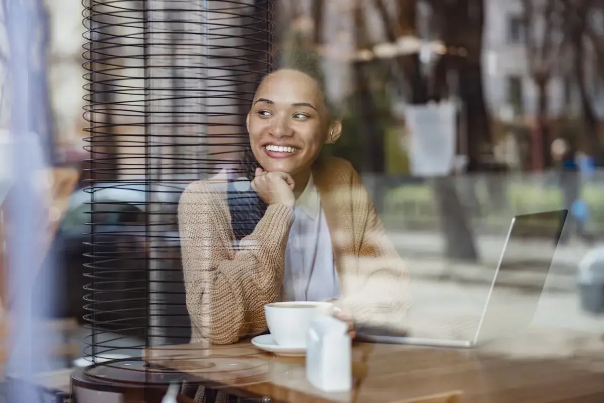 Een medewerker lacht in een café bij het raam