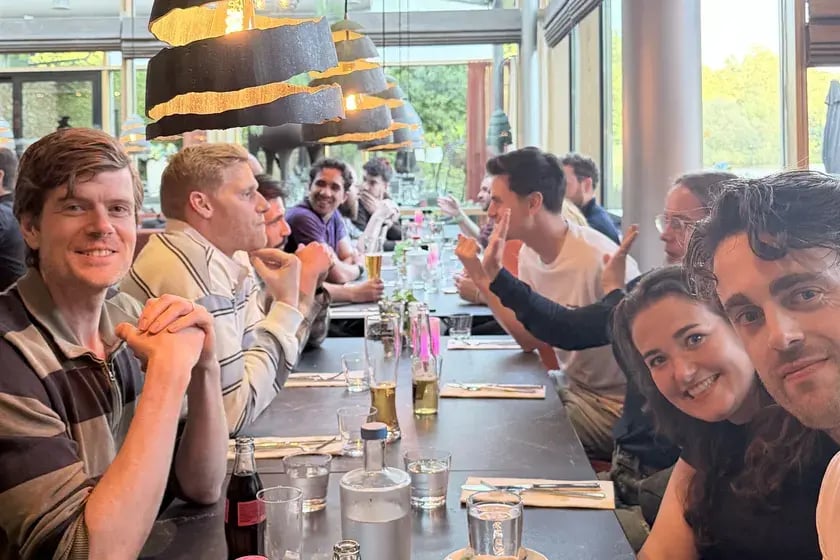 Collega’s lachen in de camera aan een lange tafel tijdens een diner