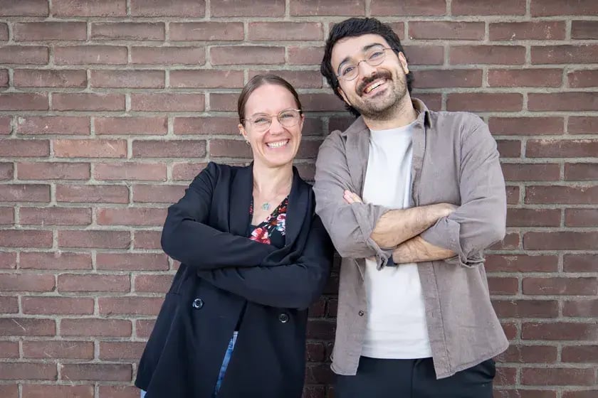 Twee collega’s lachen tegen een bakstenen muur